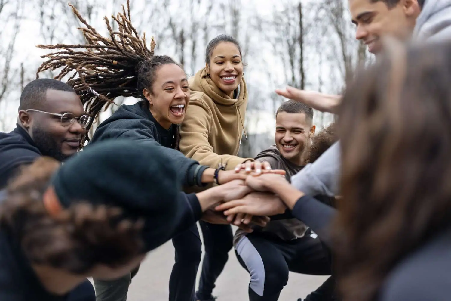 A group of smiling people coming together in a circle to support each other.